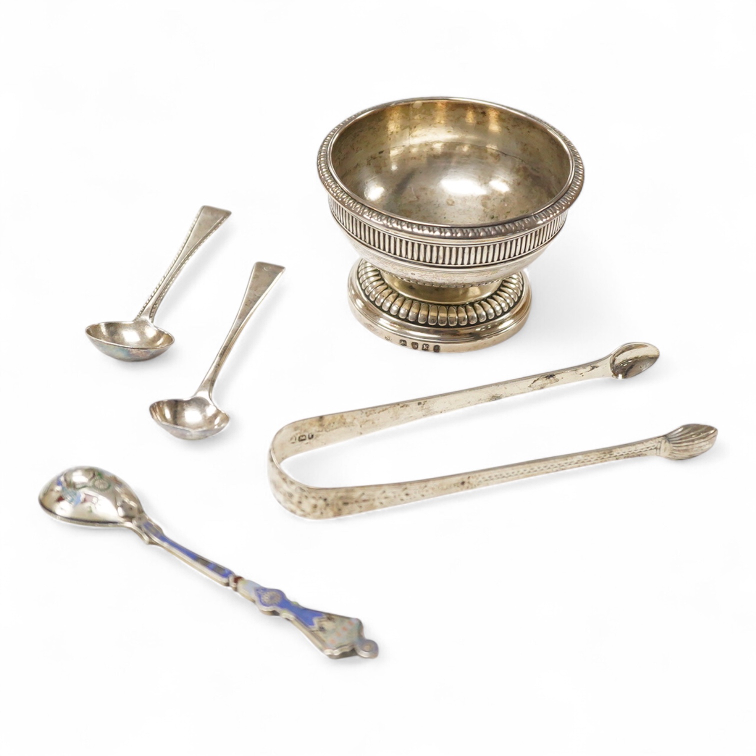 A George III silver pedestal salt, London, 1805, diameter 84mm, together with a pair of Georgian silver sugar tongs, two silver condiment spoons and a Russian 84 zolotnik and polychrome cloisonne enamel spoon, 11.1cm.